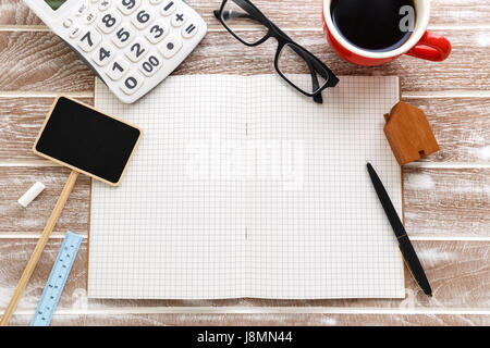 Blank notebook con casa in vendita segno e la calcolatrice per tasse di proprietà e concetto di ipoteca Foto Stock