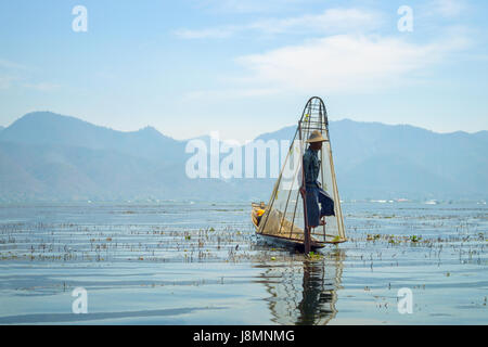Pescatore birmano sulla barca di bambù per la cattura di pesce in modo tradizionale con la rete a mano. Lago Inle, Myanmar (Birmania), meta di viaggio