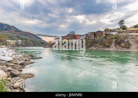 Cielo drammatico a Rishikesh, santa città e destinazioni di viaggio in India. Colorato Cielo e nubi riflettendo sopra il fiume Gange. Foto Stock