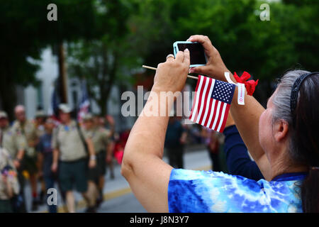 Westminster, Maryland, Stati Uniti d'America. 29 Maggio, 2017. Una donna che mantiene una bandiera americana usa il suo smartphone per scattare foto delle sfilate per il Memorial Day, una vacanza federale degli Stati Uniti per ricordare coloro che morirono mentre erano in servizio nelle forze armate. Credito: James Brunker/Alamy Live News Foto Stock