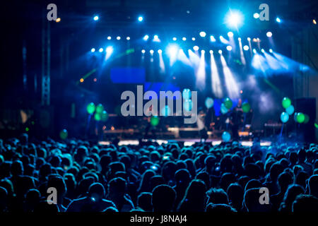 Sagome di concerto folla davanti a bright stage luci. movimento dell'immagine. Foto Stock