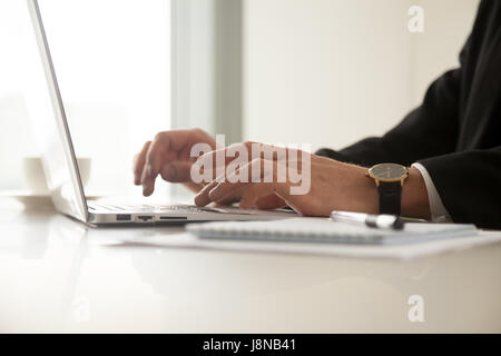 Chiudere l immagine di ragazzi le mani in un orologio da polso digitazione sul computer portatile in ufficio. Imprenditore lavorando sul computer al lavoro. Lavoratore di ufficio navigando su internet, Foto Stock