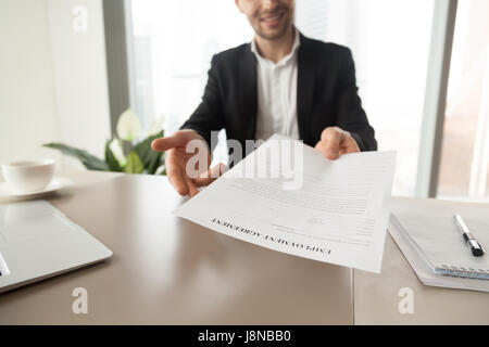 Responsabile assunzioni raggiungendo foglio con contratto di lavoro. CEO sorridente offre per leggere e controllare le condizioni di lavoro, li invita a firmare il documento. Scendete Foto Stock