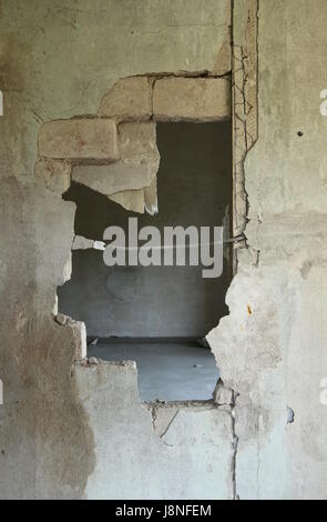 Foro rotto attraverso un vecchio muro di mattoni. Foto Stock