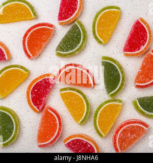 Colorata gelatina di frutta di agrumi viene diffusa in maniera casuale su una tabella grigia top Foto Stock