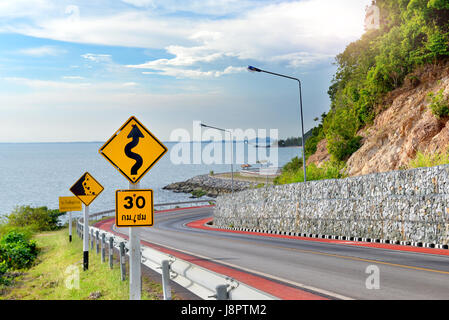 Il simbolo di avvertimento segno per protecion del traffico nella strada di montagna foto in sun illuminazione. Foto Stock