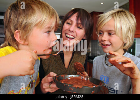 Jenny Lewis la cottura nella sua casa di Eastington, vicino a Stroud, Gloucestershire, con figli Ollie (6), giallo camicia, e Josh (12) Foto Stock