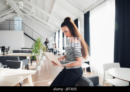 Immagine Di Donna con computer portatile mentre è seduto in un bar. Imprenditrice adulti seduti in una sala e di lavorare su un personal computer. Foto Stock