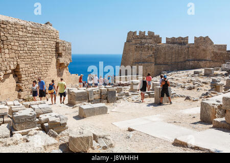LINDOS, l' isola di Rodi, Grecia - 3 Settembre 2015: turisti visitano le rovine che si affaccia sul blu del Mar Egeo dall'antica acropoli di Lindos, Rodi Foto Stock