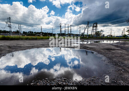 Cielo nuvoloso riflessa nella grande pozza di strada vicino a Mosca, Russia Foto Stock