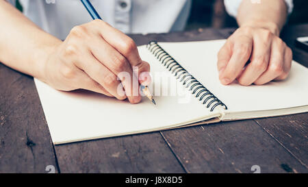 La donna la scrittura a mano di appunti sul tavolo di legno nella caffetteria. Foto Stock