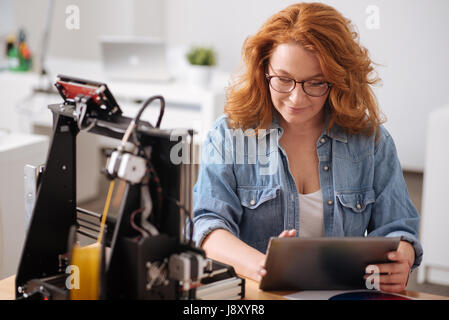 Piacevole donna positiva tenendo un tablet Foto Stock