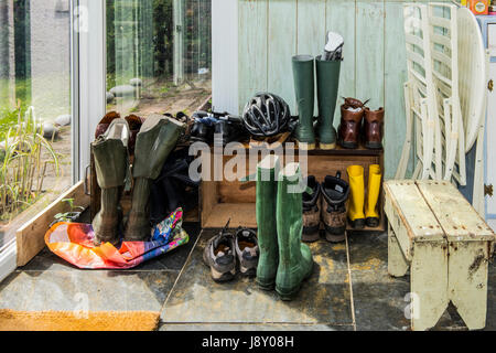 Stivali e scarpe su rack all'interno della hall di entrata/conservatorio di casa Foto Stock