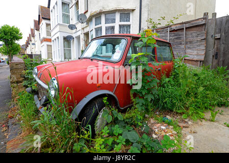 La British Leyland Mini sta decadendo e si arrugginisce in un vialetto di strada sovradimensionato a Westcliff sul Sea Essex. Con disco fiscale. Mini originale Foto Stock