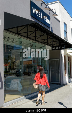 Giovane donna camminare davanti a un West Elm home decor store su south Granville Street quartiere dello shopping di Vancouver, British Columbia, Canada Foto Stock