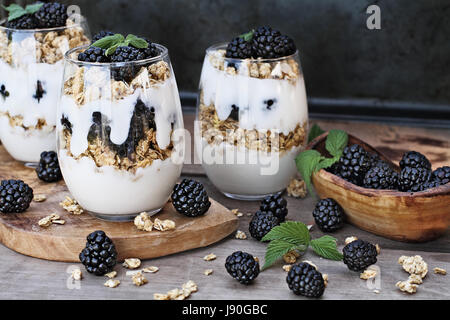 Blackberry parfaits fatta con lo yogurt greco, granola e fresco di more. Estrema profondità di campo con il fuoco selettivo su parfait in foregrou Foto Stock