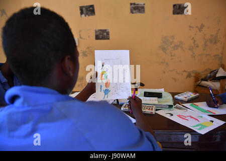 (170531) -- Mogadiscio, 31 maggio 2017 (Xinhua) -- Un ragazzo guarda al suo disegno presso il centro di formazione ELMAN, una organizzazione non governativa (ONG) che coopera con il Fondo delle Nazioni Unite per l'Infanzia (UNICEF), a Mogadiscio, Somalia, Marzo 22, 2017. Di anno in anno del 2017, più di 1630 bambini e adolescenti hanno preso i corsi di formazione professionale come quello automobilistico, manutenzione elettrica di base la conoscenza e la manutenzione del circuito di competenze, telefono cellulare e la riparazione dei computer utilizzando. La grande maggioranza degli studenti qui erano ex bambini soldato o colpiti da gruppi armati. Le conoscenze e le competenze th Foto Stock