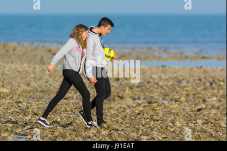 Coppia giovane facendo una passeggiata serale lungo la spiaggia di mano in mano. Foto Stock