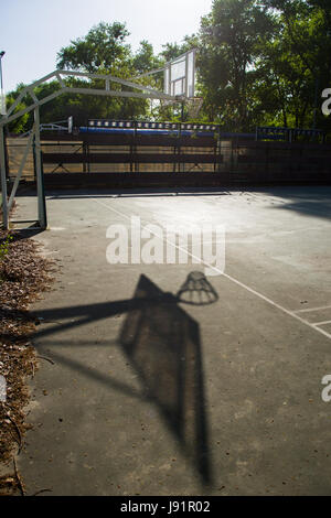 Solitaria, Basketball hoop sulla luce blu corte di asfalto nel parco giochi a scuola Foto Stock