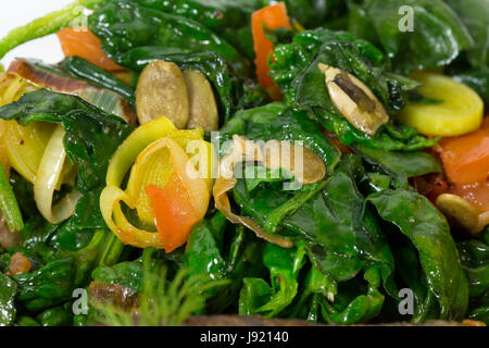 Warm insalata di spinaci con porri come guarnizione per cotto dorado. Macro. Foto può essere usato come un intero sfondo. Foto Stock