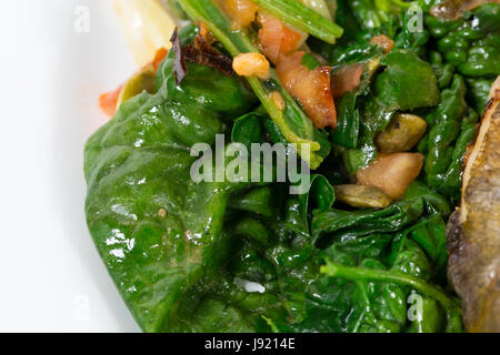 Warm insalata di spinaci con porri come guarnizione per cotto dorado. Macro. Foto può essere usato come un intero sfondo. Foto Stock