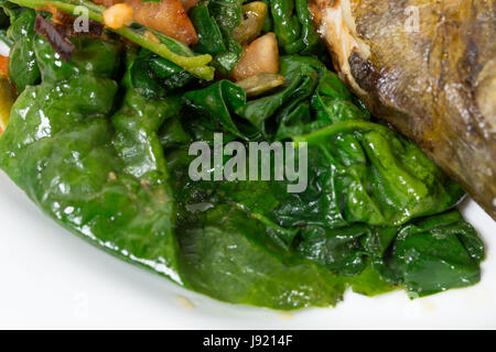 Warm insalata di spinaci con porri come guarnizione per cotto dorado. Macro. Foto può essere usato come un intero sfondo. Foto Stock