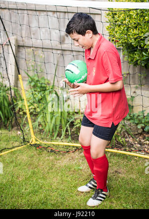 Le pratiche di Boy soccer in un giardino inglese Foto Stock