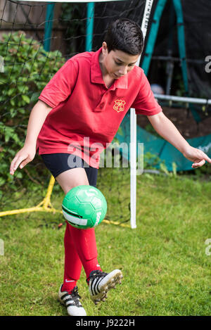 Le pratiche di Boy soccer in un giardino inglese Foto Stock