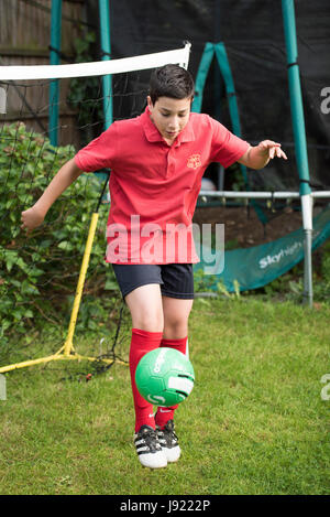 Le pratiche di Boy soccer in un giardino inglese Foto Stock