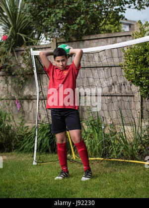 Le pratiche di Boy soccer in un giardino inglese Foto Stock