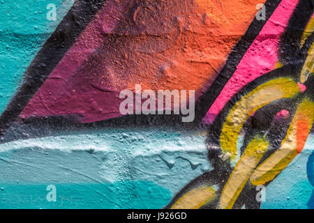 Close up di rosso, blu, rosa, arancione, giallo e nero vernice con maglie di catena dipinta su un muro di mattoni Foto Stock