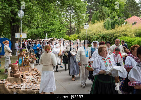 PIESTANY, Slovacchia - 20 Maggio 2017: una folla di artigiani, vestito in costumi folcloristici, marche nel parco durante il festival artigianale a Piestany Foto Stock