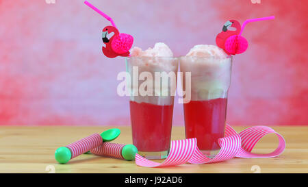 La produzione di ghiaccio in crema di soda galleggianti con rosa lampone soda e gelato a tall cafe bicchieri contro un tema rosa summer party backgroud, Foto Stock