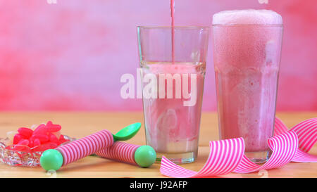 La produzione di ghiaccio in crema di soda galleggianti con rosa lampone soda e gelato a tall cafe bicchieri contro un tema rosa summer party backgroud, Foto Stock