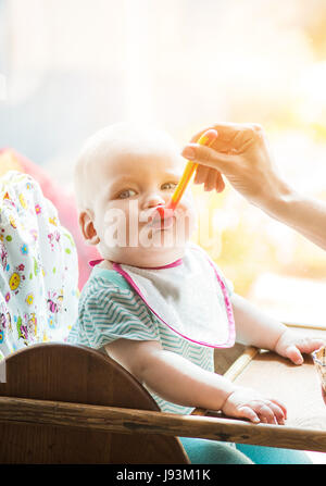 Madre alimenta funny baby da un cucchiaio Foto Stock