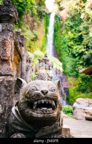 Dettagli di dragon statue in un tempio indù con cascata dietro. Gitgit, Bali, Indonesia Foto Stock