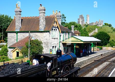 LSWR T9 classe 4-4-0 treno a vapore di entrare nella stazione ferroviaria con il castello al posteriore, Corfe, Dorset, Inghilterra, Regno Unito, Europa occidentale. Foto Stock