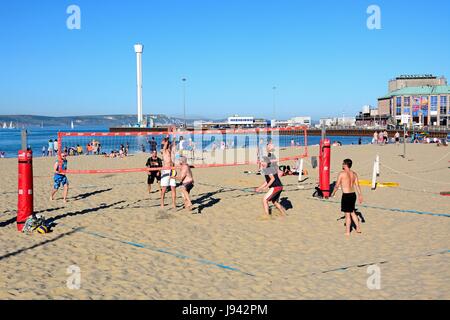 I villeggianti giocando a pallavolo sulla spiaggia con il padiglione e Jurassic Skyline tower per la parte posteriore di Weymouth Dorset, Inghilterra, Regno Unito, Europa occidentale. Foto Stock