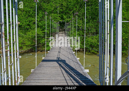 Sospensione ponte attraverso il fiume di montagna Foto Stock