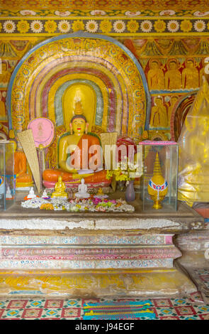 KANDY, SRI LANKA - NOVEWMBER 28, 2016: la statua di Buddha meditando circondato da modelli complessi e immagini dei suoi allievi in Natha Devale santuario, Foto Stock