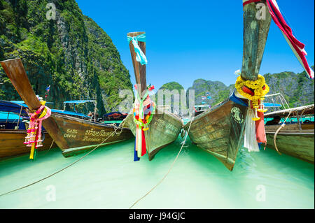 KRABI, Tailandia - 12 novembre 2014: tradizionale Thai longtail barche decorate con buona fortuna bow infissi galleggiante sotto montagne carsiche. Foto Stock