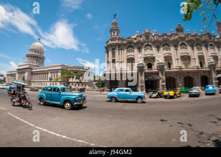 Luminoso e ampio angolo di visione della vita quotidiana in una delle strade principali di Central Havana, Cuba con i classici taxi auto passando il Capitolio Building Foto Stock