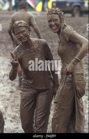 Glastonbury Festival 1998, uno degli anni peggiori per fanghi, dove i partecipanti del festival è andato a fango di balneazione tra guardare la musica dal vivo di atti. Il festival annuale attira fino a 175.000 persone per azienda agricola degna dove si può guardare spettacoli di musica dal vivo su numerosi stadi comprende la fase della piramide. Foto Stock