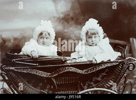 Twin Baby sorelle nella PRAM Vintage, carrozzina o passeggino Periodo da indossare vestiti del bambino e berretti c1910 Foto Stock