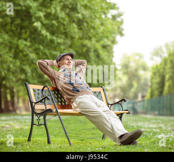 Senior relax su una panca in legno nel parco Foto Stock