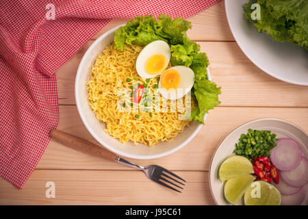 Tagliatelle istante nella ciotola con le verdure e uova sode o su uno sfondo di legno Foto Stock