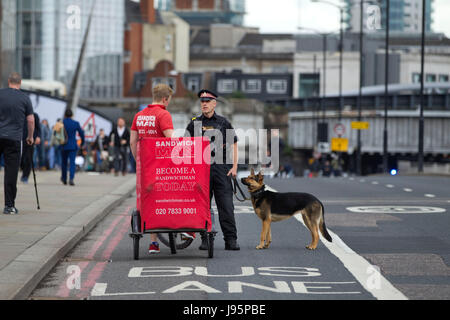 London Bridge, Londra, Regno Unito. 5° giu, 2017.Un sandwich courier è arrestato dalla polizia metropolitana cani team sul Ponte di Londra dopo la strada è chiusa al traffico dopo il week-end di attacco terroristico in cui tre terroristi ha guidato un noleggio bianco van in pedoni fine del sabato notte e poi sono andato su persone pugnalata nei bar e nelle strade di Borough Market, Central London, England UK Credit: Jeff Gilbert/Alamy Live News Foto Stock