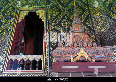 In stile thailandese finestra decorata e dorata a parete, con la scrittura sulla scatola in legno intagliato ripiano interno Ho Trai, Wat Mahathat tempio, Yasothon, Thailandia Foto Stock