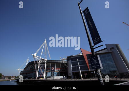 I lavoratori in discesa in corda doppia installazione ingranaggi di un banner al di fuori lo stadio nazionale del Galles (aka Principato Stadium) Foto Stock