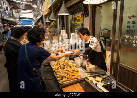 Un uomo che serve i clienti a una pressione di stallo alimentare nel mercato Tongin, Tongin Dong Seoul, Corea del Sud Foto Stock